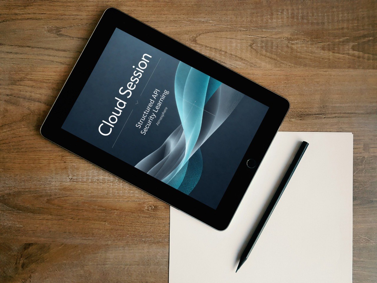 A tablet device lying on a wooden desk, angled diagonally, with a blank sheet of paper and a stylus beside it. The tablet screen displays the text 'Cloud Session' and 'Structural Java Second Language'.